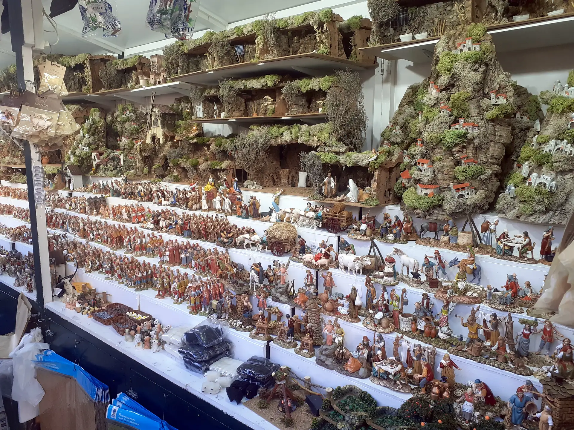 Prestatges amb figures de pessebre i escenaris de molsa en una parada de la Fira de Santa Llúcia
